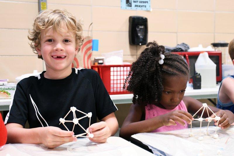 Two students build structures out of marshmallows and toothpicks